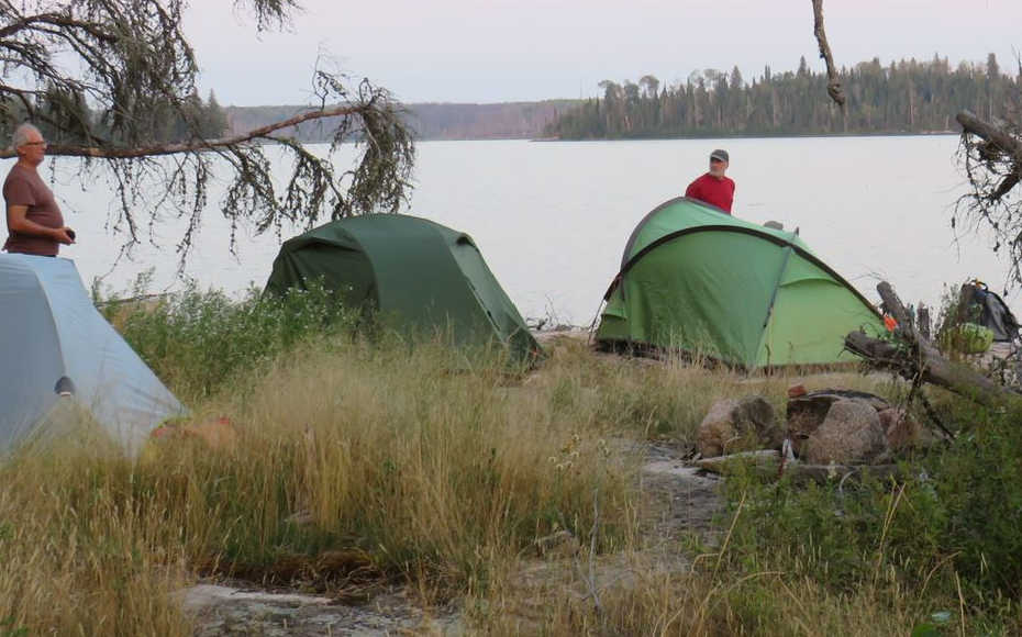 Two tents next to a lake Description automatically generated