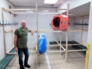 A person standing in a room with a kayak Description automatically generated