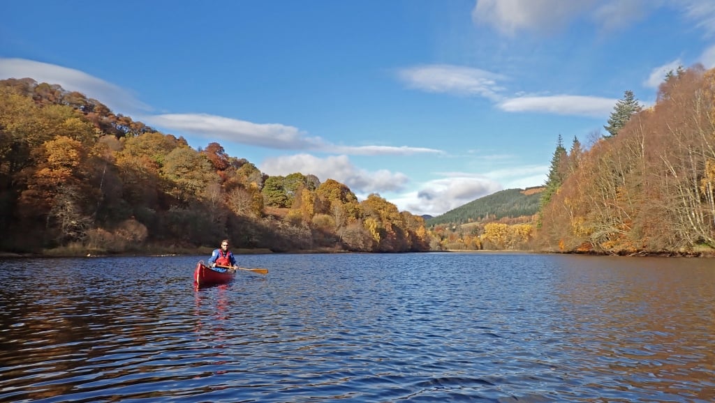 A person in a canoe on a lakeDescription automatically generated