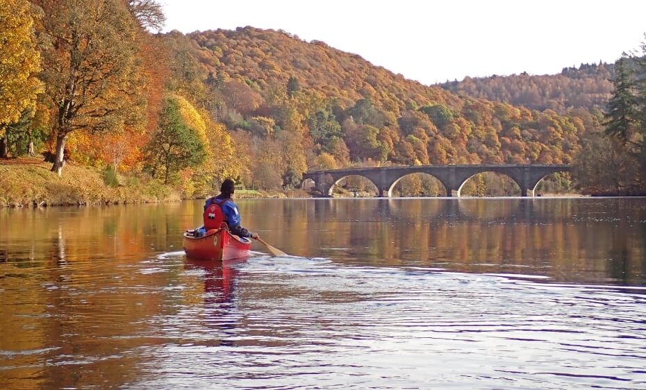 A person in a canoe on a river Description automatically generated