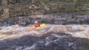 A person in a kayak in a river Description automatically generated