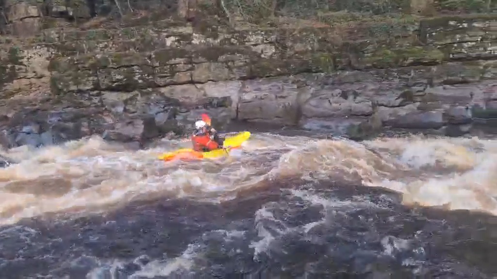 A person in a kayak in a river Description automatically generated