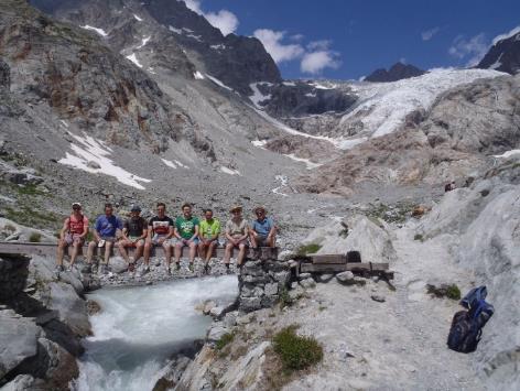 A group of people sitting on a bridge over a river Description automatically generated