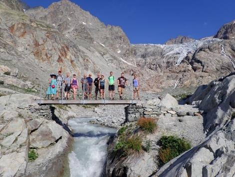 A group of people standing on a bridge over a river Description automatically generated