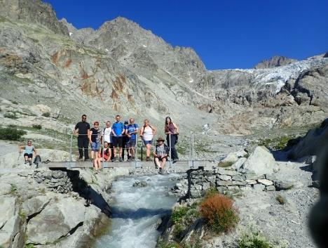 A group of people standing on a bridge over a river Description automatically generated