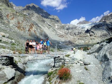 A group of people standing on a bridge over a river Description automatically generated