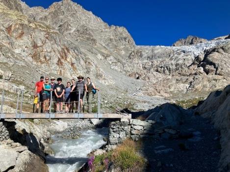 A group of people standing on a bridge over a river Description automatically generated