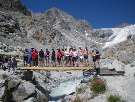 A group of people standing on a bridge over a river Description automatically generated