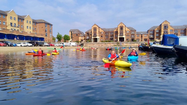A group of people in kayaks on a lakeAI-generated content may be incorrect.