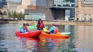 A group of people in kayaks on water AI-generated content may be incorrect.