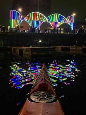A canoe on the water with colorful lightsAI-generated content may be incorrect.