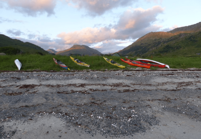 A group of kayaks on a beach Description automatically generated