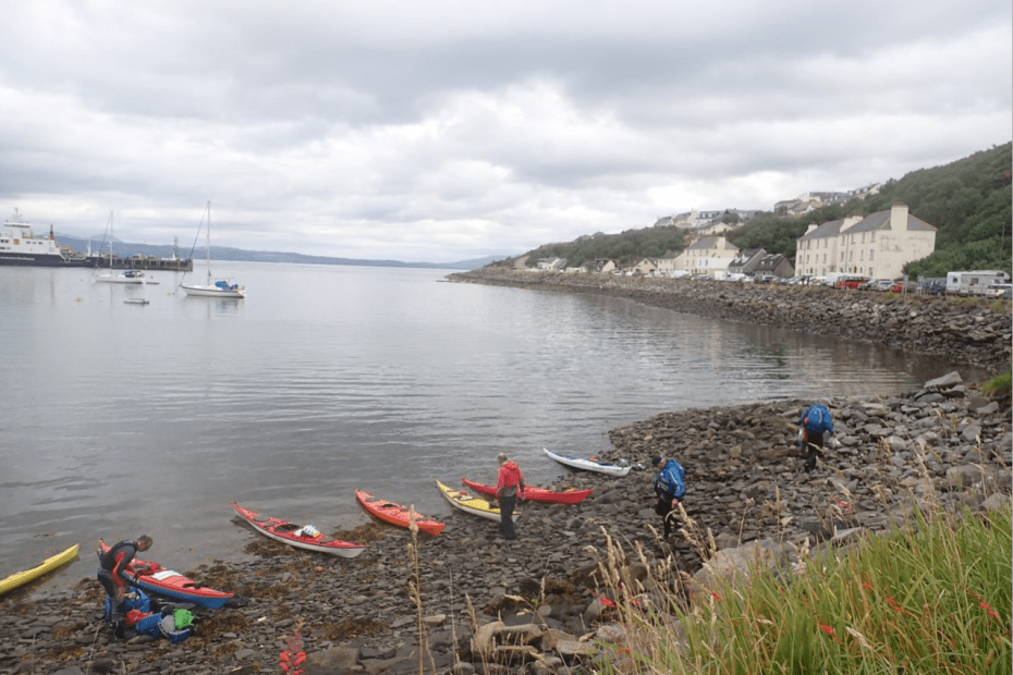 A group of people with kayaks on a rocky shore Description automatically generated