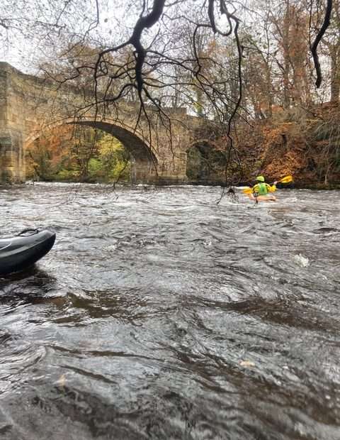 A person in a kayak in a river Description automatically generated